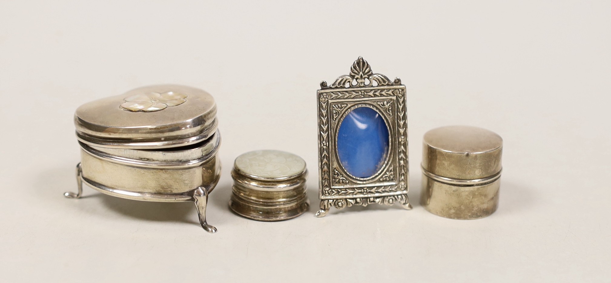 A George V silver heart shape trinket box, Saunders & Shepherd, Birmingham, 1910, 45mm, a ring box, a pill box and a small photograph frame.